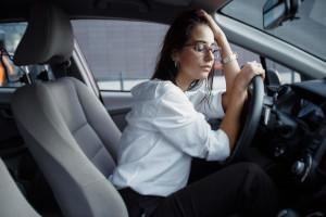 mulher triste no carro segurando o volante