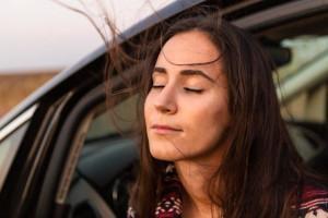 Mulher confiante dentro do carro sentindo a brisa no rosto
