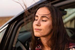 mulher inspirada de olhos fechados na janela do carro